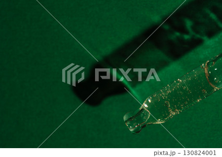Glass pipette with serum and shadow on green surface Glass pipette with serum and shadow on green surface 130824001