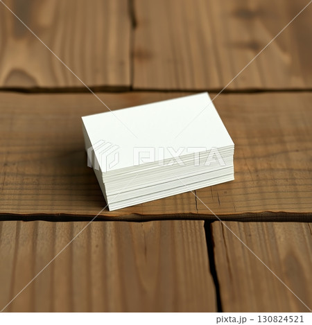 Close-up shot of a stack of white business cards on a wooden surface, focused. 130824521