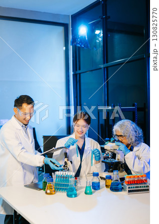 scientists conducting research investigations in a medical laboratory, a researcher in the foreground scientists conducting research investigations in a medical laboratory, a researcher in the foreground 130825770