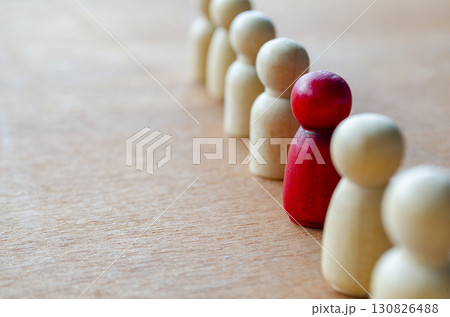 A red figurine paired with a beige figurine while others watch representing alignment that may indicate leadership or harassment 130826488