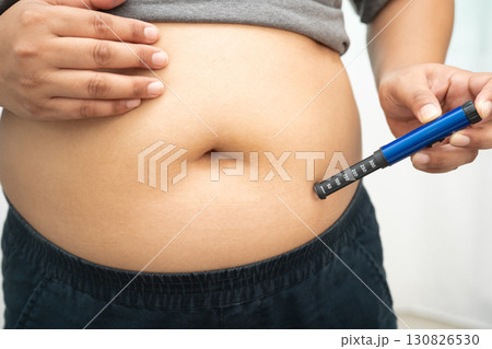 Asian woman injecting herself diabetes injecting insulin in stomach at home. Asian woman injecting herself diabetes injecting insulin in stomach at home. 130826530