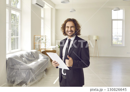 Portrait of friendly young male realtor showing thumbs up recommending his real estate agency. Portrait of friendly young male realtor showing thumbs up recommending his real estate agency. 130826645