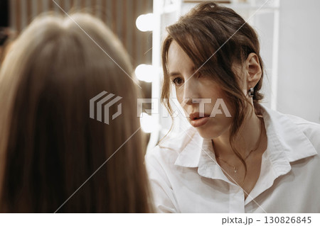 Makeup artist working on creating look for model. Focused look of makeup artist 130826845