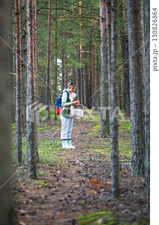Satisfied woman check freshly picked mushroom for edibility in pine forest during foraging walk Satisfied woman check freshly picked mushroom for edibility in pine forest during foraging walk 130826864