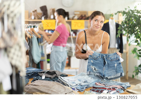Young woman choosing jean shorts in clothing store Young woman choosing jean shorts in clothing store 130827055