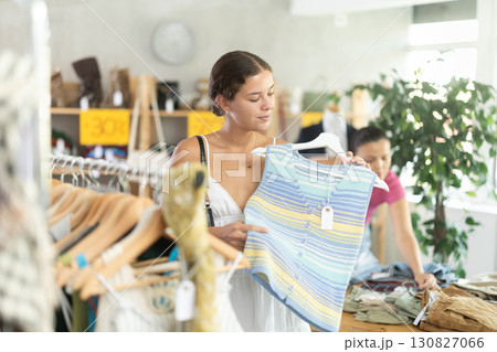 Positive joyful woman looking for fashionable clothes in clothing boutique 130827066