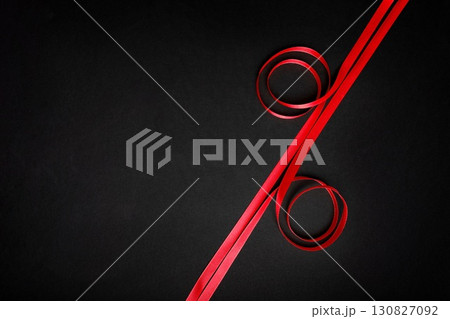 Red satin ribbons form percent sign on black background, great for sale, discount, or special offer banners 130827092