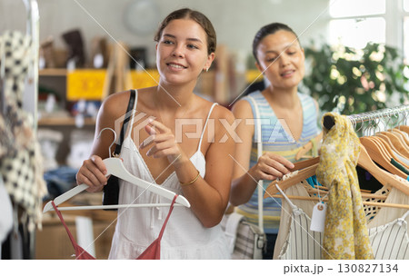 Two joyful women looking for fashionable clothes in clothing boutique Two joyful women looking for fashionable clothes in clothing boutique 130827134