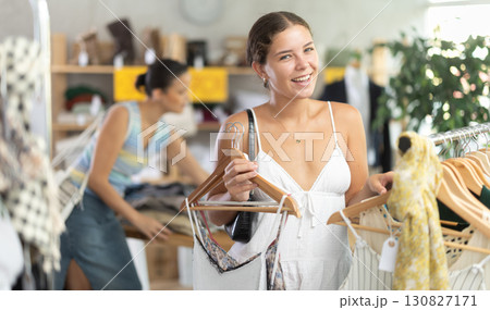 Positive young woman choosing something for summer in clothing store Positive young woman choosing something for summer in clothing store 130827171