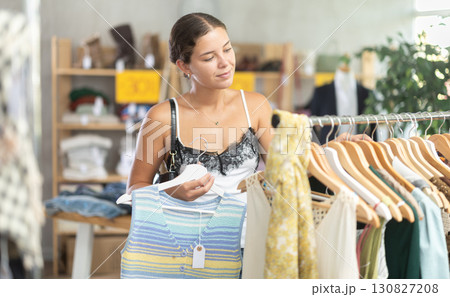Woman customer turn over and choose something clothing for summer in store 130827208