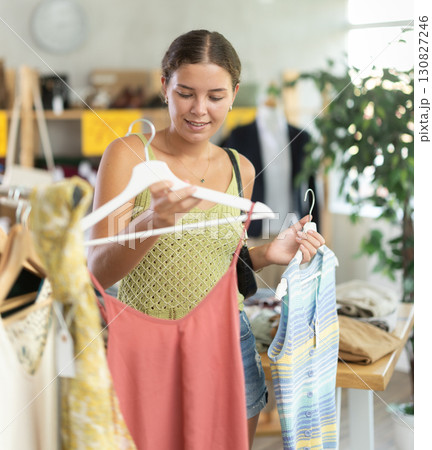 Positive joyful woman looking for fashionable clothes in clothing boutique 130827246