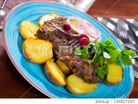 Beef steak with baked potatoes and sauce at plate with greens 130827283