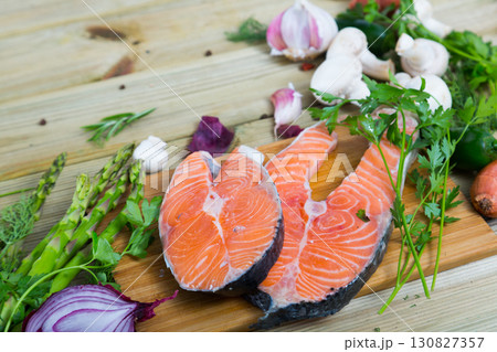 Raw salmon steaks with fresh vegetables and mushrooms on wooden desk Raw salmon steaks with fresh vegetables and mushrooms on wooden desk 130827357