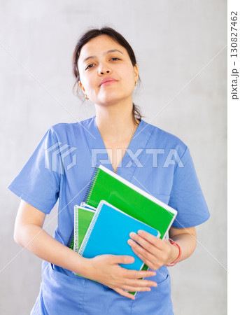 Smiling female medical student holding workbooks with lecture notes 130827462