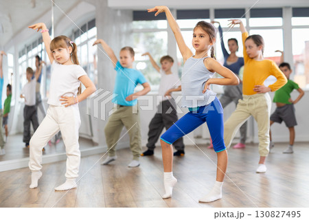 Children studying modern style dances with female teacher in dance class 130827495