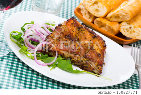Baked pork ribs baked served at plate with salad from arugula 130827571