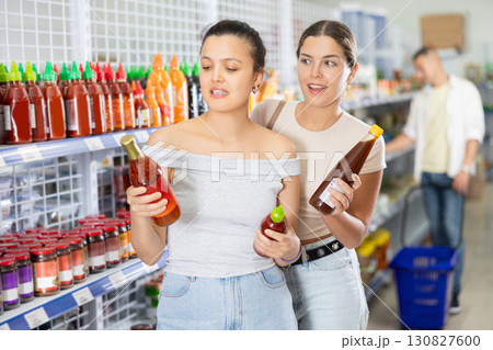 Young female friends selecting sauces in Asian grocery store Young female friends selecting sauces in Asian grocery store 130827600