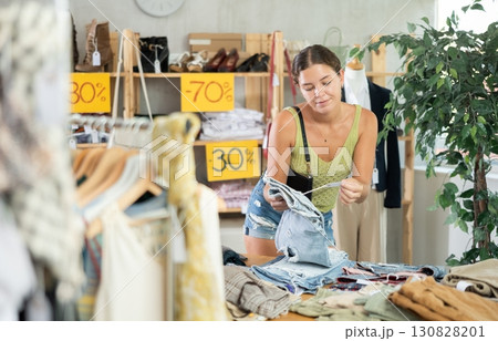 Positive young woman choosing pantaloons in clothing store Positive young woman choosing pantaloons in clothing store 130828201