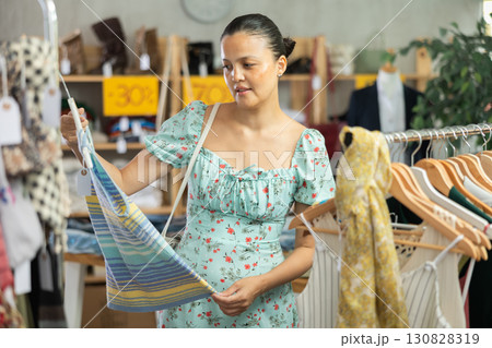 Positive joyful woman looking for fashionable clothes in clothing boutique 130828319