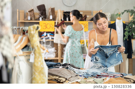 Young woman choosing jean shorts in clothing store Young woman choosing jean shorts in clothing store 130828336