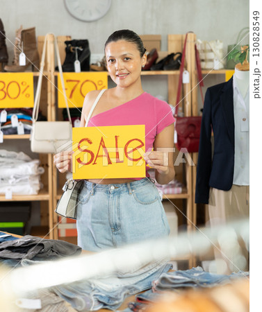 Asian woman with poster in her hands announces clothing discounts 130828549
