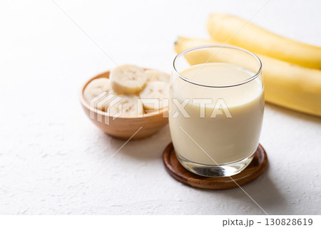 Banana milk in glass with sliced banana and fruit on white background Banana milk in glass with sliced banana and fruit on white background 130828619