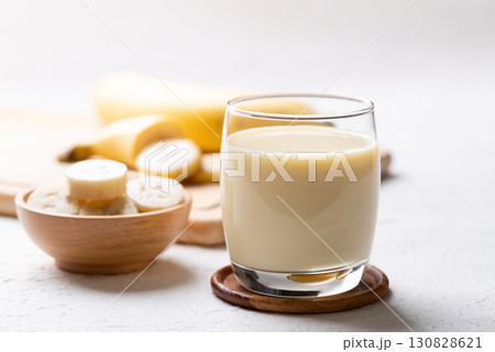 Banana milk in glass with sliced banana and fruit on white background Banana milk in glass with sliced banana and fruit on white background 130828621