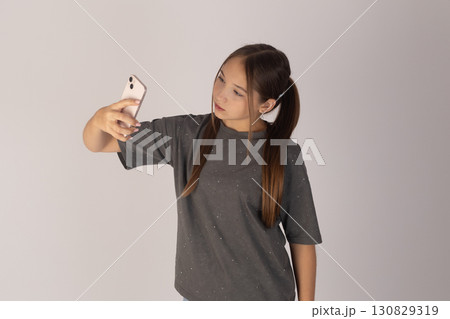 a young woman with long dark hair tied in pigtails, wearing a grey t-shirt, and 130829319