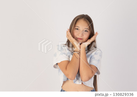 Girl is posing with her hands cupped around her face, appearing youthful and  130829336