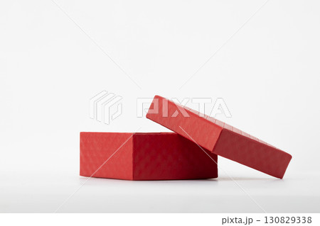 a red gift box with its lid partially open, resting on a light-colored surface a red gift box with its lid partially open, resting on a light-colored surface 130829338
