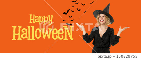 Woman with curly hair wearing a witch hat celebrates Halloween 130829755