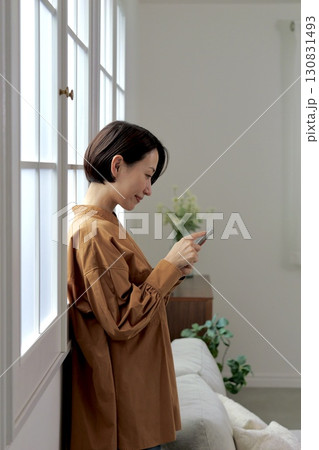 窓辺でスマホを操作する女性 窓辺でスマホを操作する女性 130831493