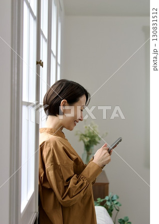 窓辺でスマホを操作する女性 窓辺でスマホを操作する女性 130831512