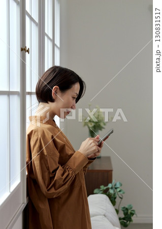 窓辺でスマホを操作する女性 130831517