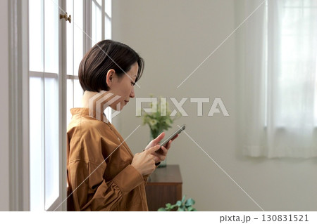 窓辺でスマホを操作する女性 窓辺でスマホを操作する女性 130831521