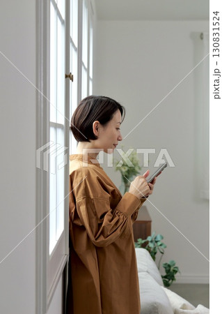 窓辺でスマホを操作する女性 窓辺でスマホを操作する女性 130831524