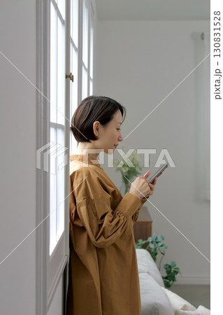 窓辺でスマホを操作する女性 窓辺でスマホを操作する女性 130831528