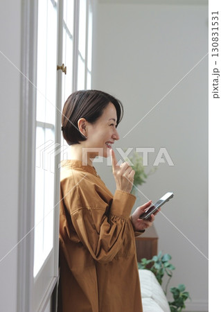 窓辺でスマホを操作する女性 窓辺でスマホを操作する女性 130831531