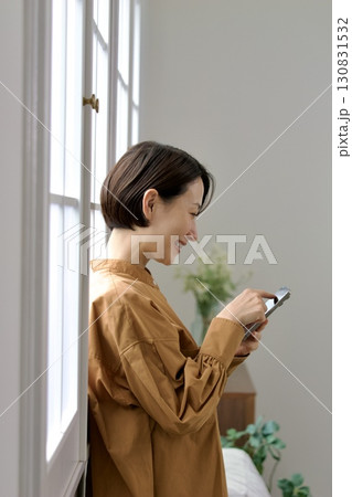 窓辺でスマホを操作する女性 窓辺でスマホを操作する女性 130831532