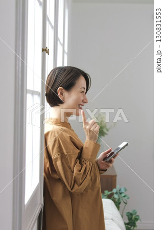 窓辺でスマホを操作する女性 窓辺でスマホを操作する女性 130831553