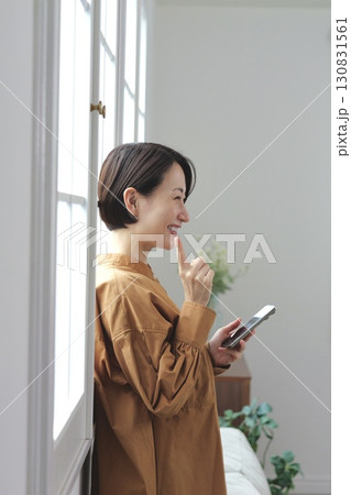 窓辺でスマホを操作する女性 窓辺でスマホを操作する女性 130831561