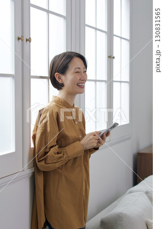 窓辺でスマホを操作する女性 窓辺でスマホを操作する女性 130831565