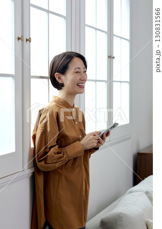 窓辺でスマホを操作する女性 窓辺でスマホを操作する女性 130831566