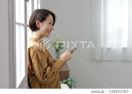 窓辺でスマホを操作する女性 窓辺でスマホを操作する女性 130831567