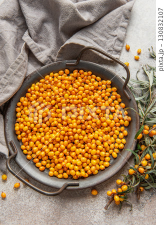 Fresh sea buckthorn berries filling a metal tray on a textured surface Fresh sea buckthorn berries filling a metal tray on a textured surface 130832107