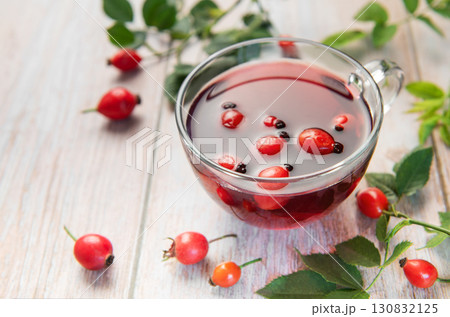 Rosehip tea brewing in glass cup on rustic wooden table Rosehip tea brewing in glass cup on rustic wooden table 130832125