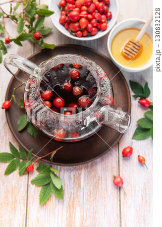 Steaming rosehip tea brewing in glass teapot with honey and fresh rose hips Steaming rosehip tea brewing in glass teapot with honey and fresh rose hips 130832128
