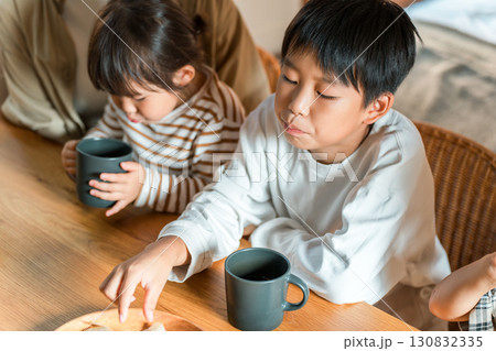 3時のおやつにスナック菓子,ポテトチップスを食べる親子 130832335