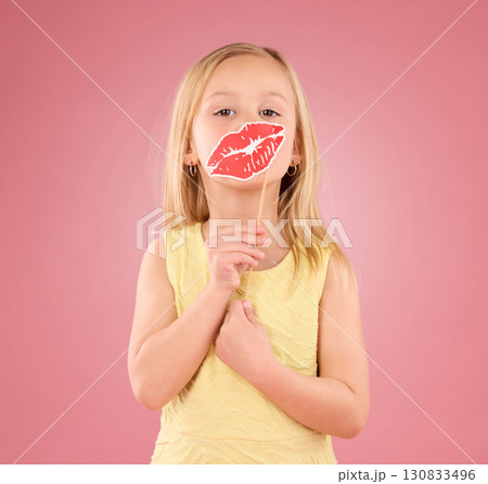 Portrait, children and lips with a girl on a pink background in studio holding a mouth prop. Kids, emoji and kiss with an adorable little female child holding a cardboard shape for valentines day 130833496