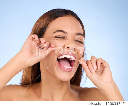 Dental floss, tooth cleaning and woman smile with teeth hygiene, healthcare and wellness treatment. Isolated, blue background and studio with a female feeling beauty from a clean mouth with self care Dental floss, tooth cleaning and woman smile with teeth hygiene, healthcare and wellness treatment. Isolated, blue background and studio with a female feeling beauty from a clean mouth with self care 130833845